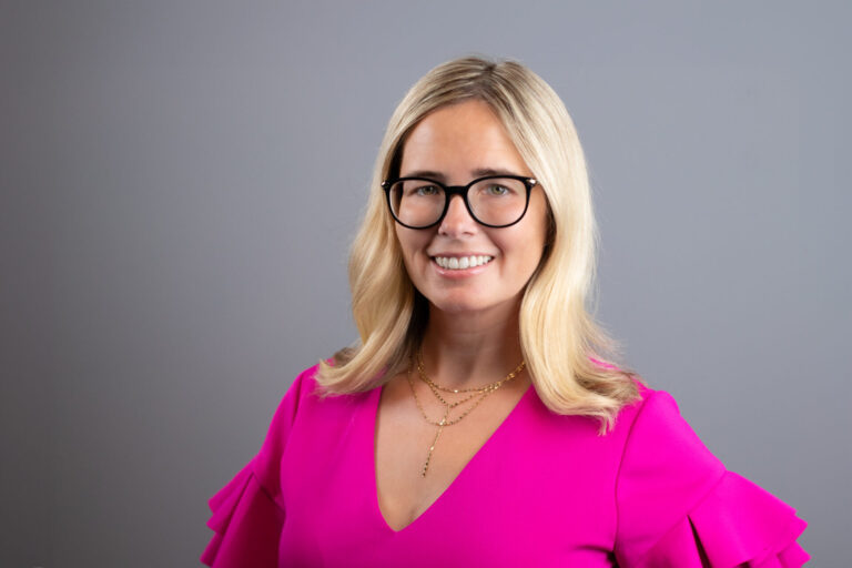 Metro Detroit real estate agent Leslie Martin wearing hot pink dress on grey background